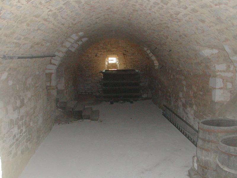 Photo d’illustration : une cave voûtée en pierre, vide, avec de la lumière au fond.