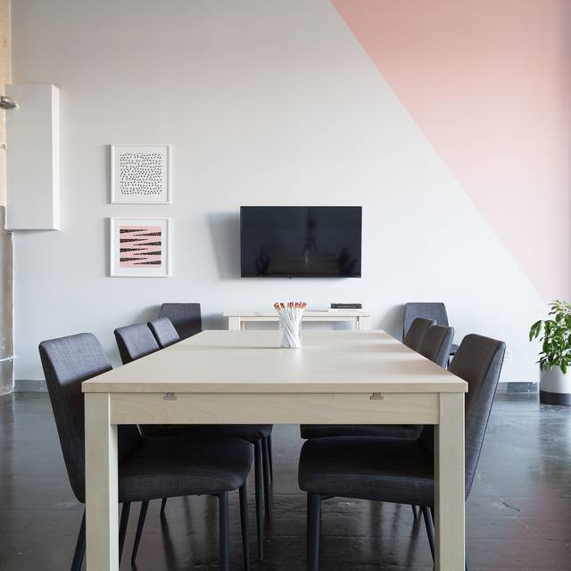 Photo d’illustration : une salle de réunion avec une table claire, des chaises sombres et un écran au mur.