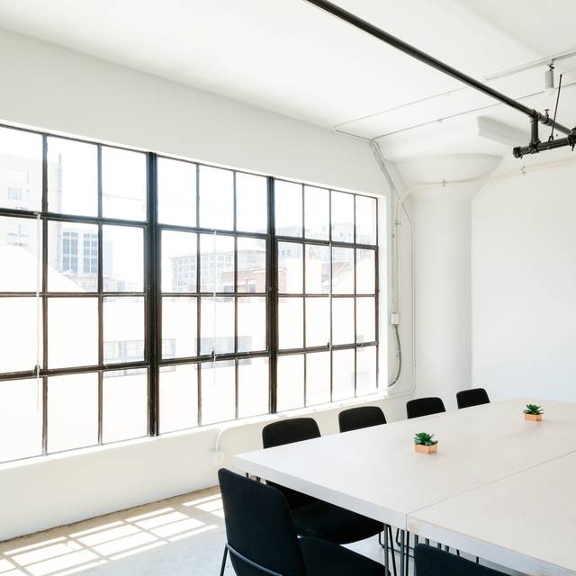 Photo d’illustration : une salle lumineuse à grandes verrières noires, avec une table de réunion blanche.
