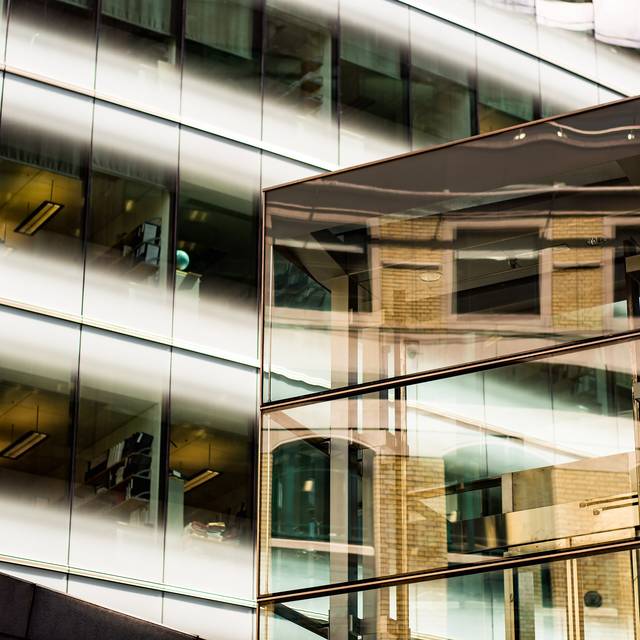 Photo d’illustration : la façade vitrée d’un immeuble, avec des reflets de bâtiments.