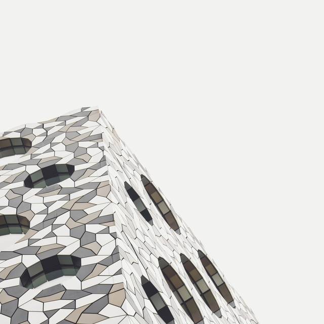 Photo d’illustration : l’angle d’un immeuble à façade en mosaïque, sur un ciel clair.