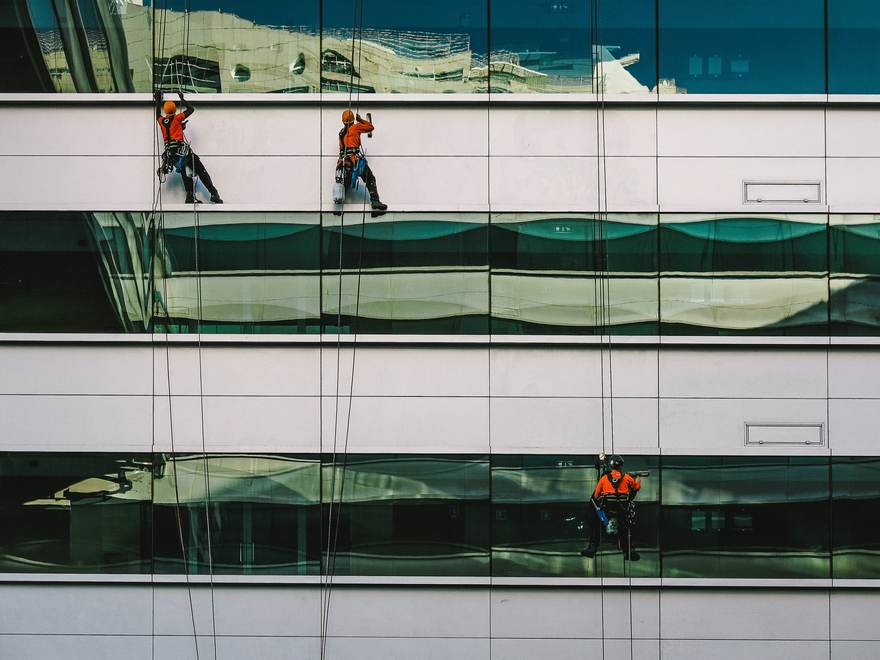 Photo d’illustration : trois laveurs de vitres en rappel travaillent sur la façade vitrée d’un immeuble.